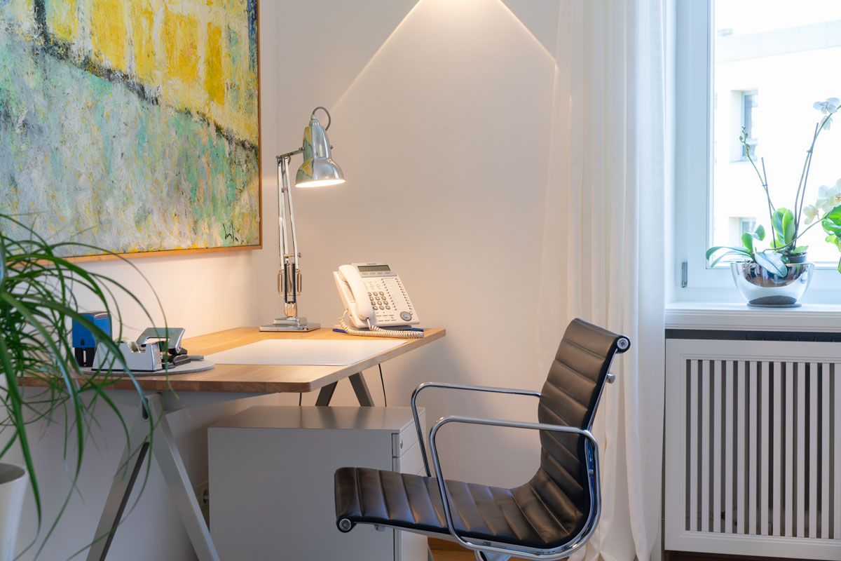 Schreibtisch mit Lampe und Telefon in einem modernen Behandlungsraum der Praxis von Franziska Karlbauer